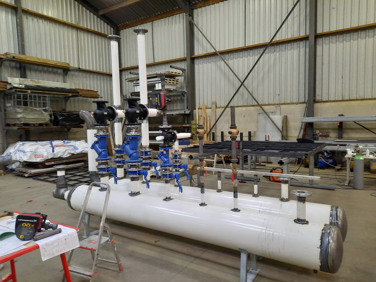 Industrieel leidingwerk met blauwe kleppen en witte pijpen in een werkplaats